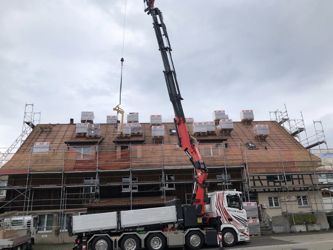 Grand chantier de toiture avec grue et palettes de tuiles